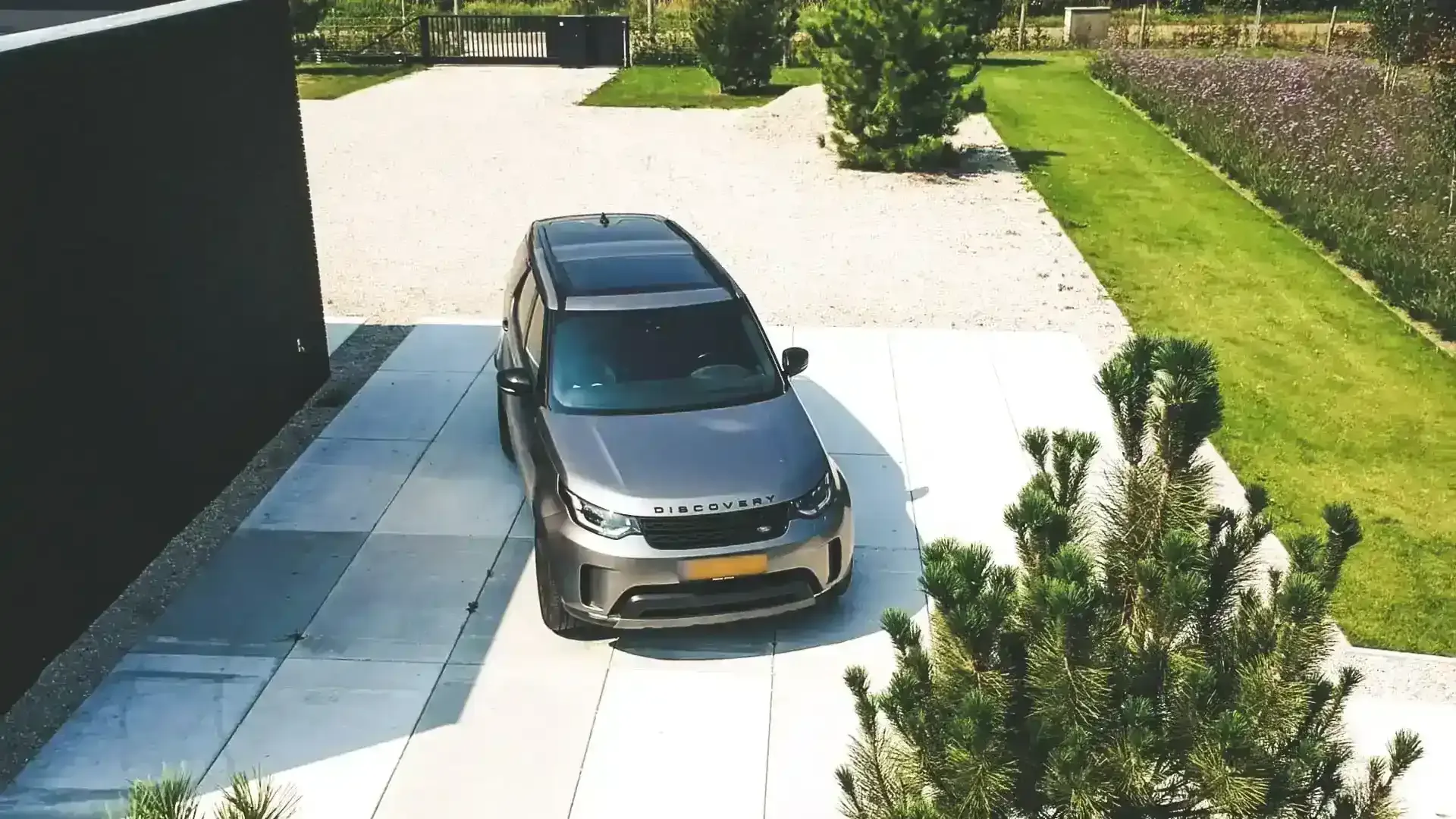 Oprit van betonplaten met een geparkeerde auto voor een moderne woning