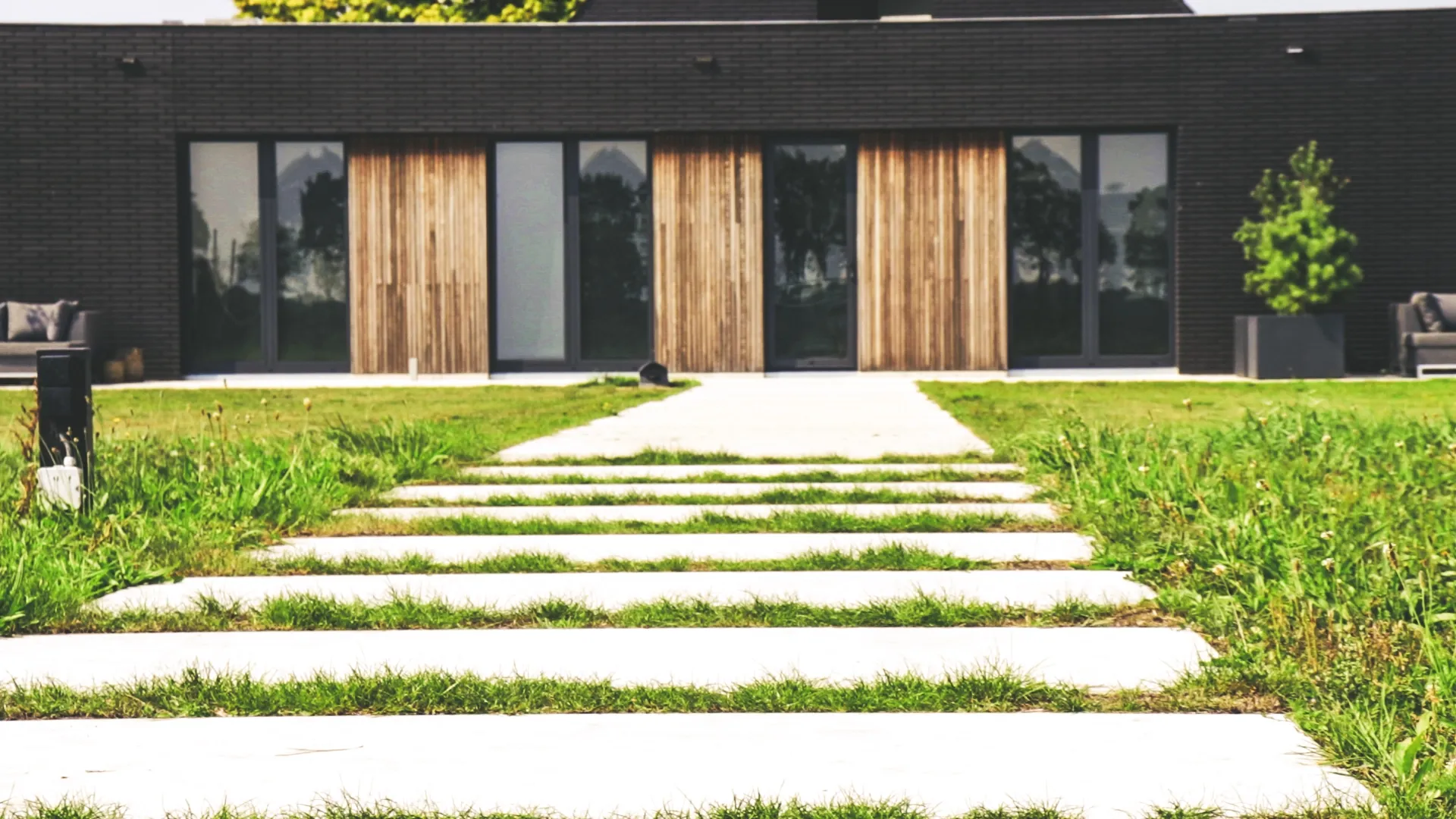 Looppad van betonplaten door het gras naar een moderne woning
